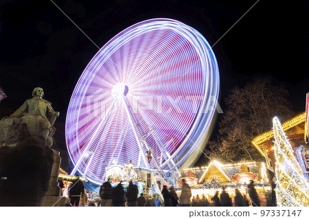 Scenic view of traditional old german Christmas market square in Magdeburg with light decoration illuminated ferris wheel, historical Otto monument and people. Christmas new Year celebration winter 97337147