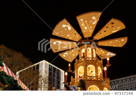 Beautiful traditional German Christmas Market square in Magdeburg city center Germany with Christmas Pyramide many carousel, tree lights and decoration. Christmas and new year celebration season Beautiful traditional German Christmas Market square in Magdeburg city center Germany with Christmas Pyramide many carousel, tree lights and decoration. Christmas and new year celebration season 97337149