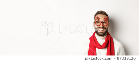 Christmas, New Year and celebration concept. Close-up of happy bearded man smiling, wearing party glasses and red scarf, white background Christmas, New Year and celebration concept. Close-up of happy bearded man smiling, wearing party glasses and red scarf, white background 97339120
