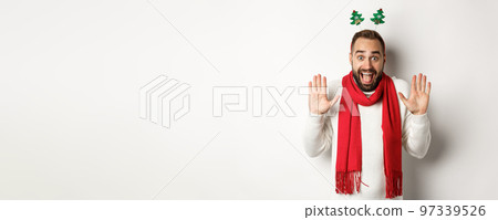 Christmas holidays. Excited bearded man raising hands up and shouting for joy, celebrating New Year party, standing against white background 97339526