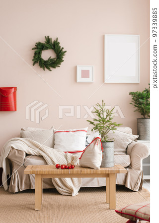 Stylish Christmas living room interior with sofa, coffee table, Christmas tree and wreath, mailbox, gifts and decorations. Festive time for the family. 97339885