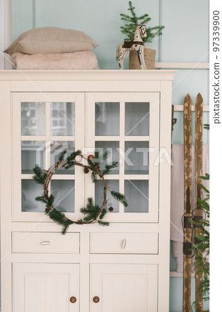 White wardrobe with a Christmas wreath, skis and decor in the living room of the house 97339900