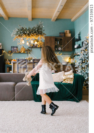 Cute little girl dancing near the Christmas tree. Children's joy In the new year holidays Cute little girl dancing near the Christmas tree. Children's joy In the new year holidays 97339915