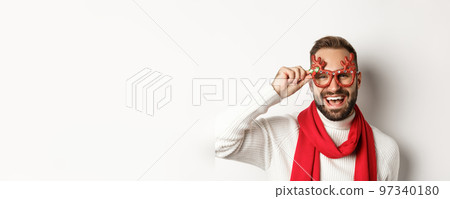 Christmas, New Year and celebration concept. Happy bearded guy in party glasses laughing and enjoying winter holidays, white background Christmas, New Year and celebration concept. Happy bearded guy in party glasses laughing and enjoying winter holidays, white background 97340180