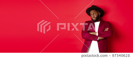 Reluctant and upset african american man looking away, cross arms on chest offended, standing distressed against red background 97340628