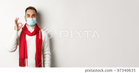 Covid-19, lockdown and quarantine concept. Satisfied handsome guy in face mask showing ok sign, approve or agree, like something, white background Covid-19, lockdown and quarantine concept. Satisfied handsome guy in face mask showing ok sign, approve or agree, like something, white background 97340635