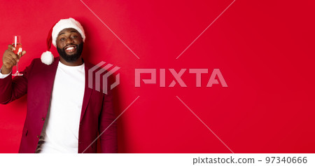 Christmas, party and holidays concept. Cheerful Black man saying cheers, raising glass of champagne and wishing happy New Year, standing against red background 97340666