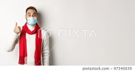 Covid-19, lockdown and quarantine concept. Amazed and satisfied man buyer in medical mask showing thumb-up, looking excited, like something good, white background Covid-19, lockdown and quarantine concept. Amazed and satisfied man buyer in medical mask showing thumb-up, looking excited, like something good, white background 97340839