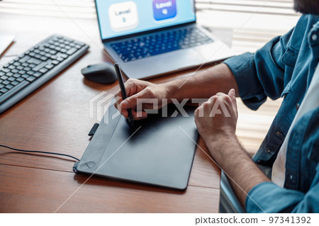 Male designer works in home office drawing on graphic tablet. Freelancer working on project Male designer works in home office drawing on graphic tablet. Freelancer working on project 97341392