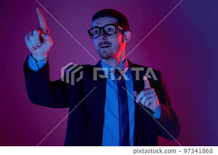 New idea. Portrait of young caucasian businessman in business suit and eyewear looking with thoughtful facial expression over purple background. New idea. Portrait of young caucasian businessman in business suit and eyewear looking with thoughtful facial expression over purple background. 97341868