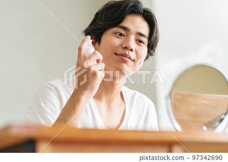 Young man applying lotion on his face 97342690