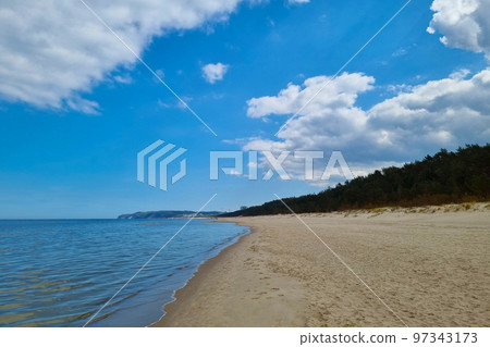 View of the Baltic sandy coast. Splashes of water. Sunny day on the beach. Seascape. Change in nature, climate. 97343173