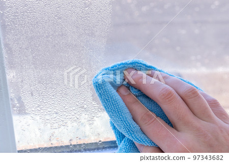 Condensation on windows in winter, wiping with a dry cloth Condensation on windows in winter, wiping with a dry cloth 97343682