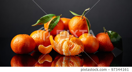 Tangerines or clementines with green leaves on a black background. Tangerines or clementines with green leaves on a black background. 97344161