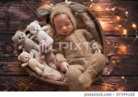Newborn baby 10 days old in knitted deer costume and bear toys for Christmas Newborn baby 10 days old in knitted deer costume and bear toys for Christmas 97344188