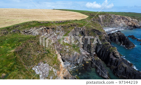 Farm fields on the shore of the Celtic Sea, south of Ireland, County Cork. Beautiful coastal area. Turquoise waters of the Atlantic. Picturesque stone hills. Drone photo. 97344219