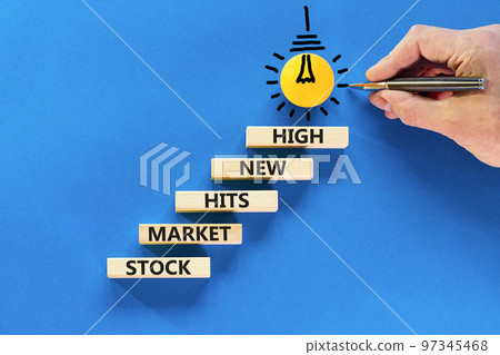 Stock market hits new high symbol. Concept words Stock market hits new high on wooden blocks on a beautiful blue background. Businessman hand. Business stock market hits new high concept. Copy space. Stock market hits new high symbol. Concept words Stock market hits new high on wooden blocks on a beautiful blue background. Businessman hand. Business stock market hits new high concept. Copy space. 97345468