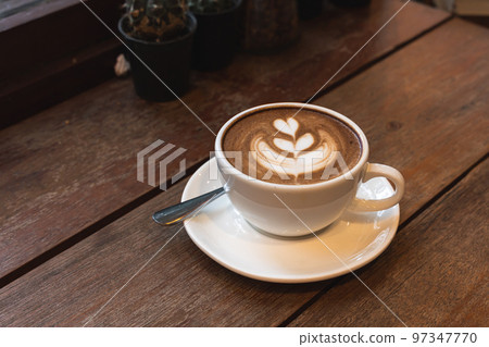 Hot coffee latte with latte art milk foam in cup mug on black wood desk on  top view. As breakfast In a coffee shop at the cafe,during business work  concept Stock Photo