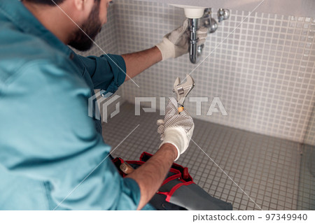 Close up of plumber is repairing faucet of a sink at bathroom using adjustable wrench 97349940