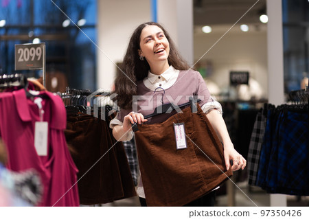 Shopping in secondhand. Happy smiling young Caucasian woman find best skirt. Concept of thrift store and sale Shopping in secondhand. Happy smiling young Caucasian woman find best skirt. Concept of thrift store and sale 97350426