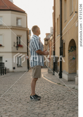 A middle-aged male tourist is looking at the sights in an old European town A middle-aged male tourist is looking at the sights in an old European town 97355296
