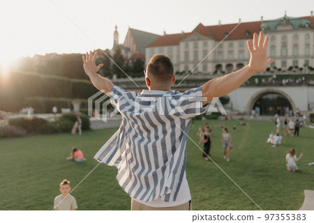 A photo from the back of the man with outstretched hands in the royal garden A photo from the back of the man with outstretched hands in the royal garden 97355383