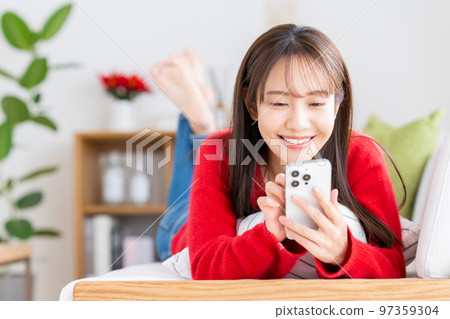 年輕女子在客廳看智慧型手機 97359304