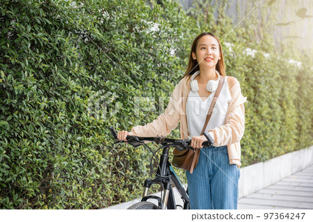 Happy female smiling walk down the street with her bike on city road, ECO environment, healthy holiday travel, Asian young woman walking alongside with bicycle on summer in park countryside outdoor Happy female smiling walk down the street with her bike on city road, ECO environment, healthy holiday travel, Asian young woman walking alongside with bicycle on summer in park countryside outdoor 97364247