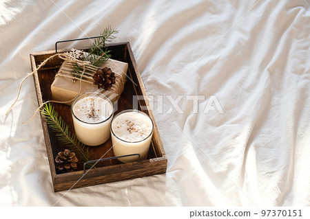 Christmas cozy morning in bed. Gift box and eggnog on wooden tra Christmas cozy morning in bed. Gift box and eggnog on wooden tra 97370151