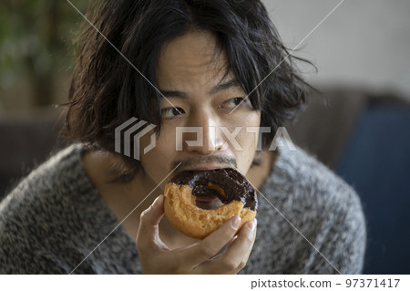 young man eating a donut 97371417