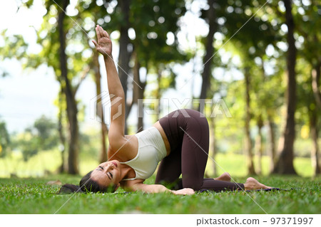 Full length of strong woman doing yoga exercise on green grass in the calm nature park in sunny day Full length of strong woman doing yoga exercise on green grass in the calm nature park in sunny day 97371997