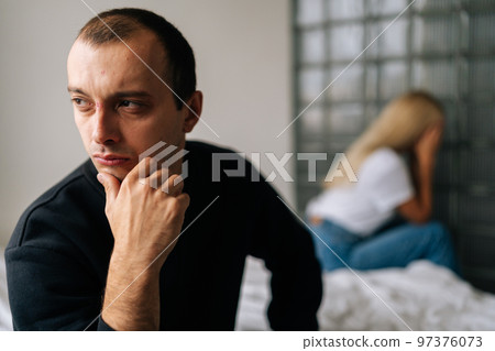 Close up face of thoughtful young man looking away not talking after dispute with sad wife sitting apart on bed. Depressed married couple sitting separate on sofa having relationships problem. Close up face of thoughtful young man looking away not talking after dispute with sad wife sitting apart on bed. Depressed married couple sitting separate on sofa having relationships problem. 97376073