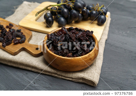 Dried black raisins in wooden spoon with fresh ripe grapes. Healthy snack, dietary product. 97376786