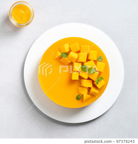 Delicious glazed mango no baked cheese cake with fresh diced mango pulp topping on bright table background. Delicious glazed mango no baked cheese cake with fresh diced mango pulp topping on bright table background. 97378243