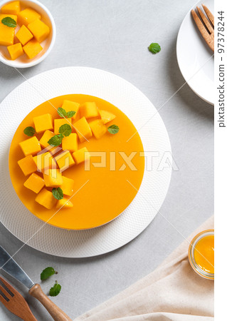 Delicious glazed mango no baked cheese cake with fresh diced mango pulp topping on bright table background. 97378244