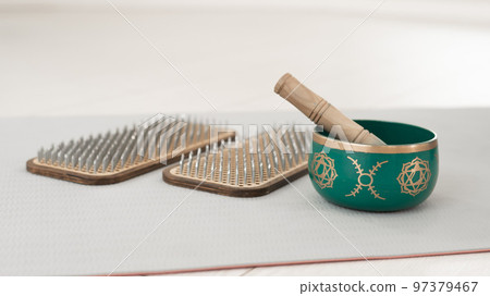 Tibetan singing bowl and sadhu board on yoga mat. Tibetan singing bowl and sadhu board on yoga mat. 97379467