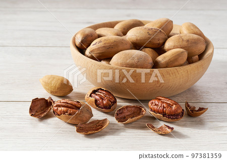 Pecan in wooden bowl on white table. Pecan in wooden bowl on white table. 97381359