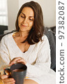 Cute brunette millenial woman in the most cozy season of the year at home drinking hot beverage 97382087