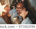 Happy interracial couple celebrating New Year at home together, sitting by Christmas tree 97382096