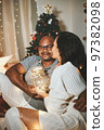 Happy interracial couple celebrating New Year at home together, sitting by Christmas tree 97382098