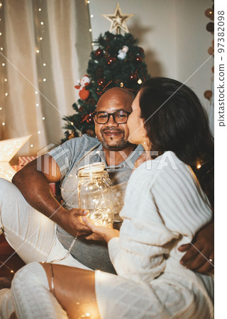Happy interracial couple celebrating New Year at home together, sitting by Christmas tree Happy interracial couple celebrating New Year at home together, sitting by Christmas tree 97382098