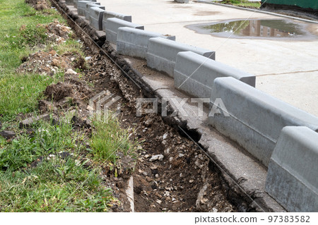 New curbs stand at the edge of the sidewalk. Preparing to repair road New curbs stand at the edge of the sidewalk. Preparing to repair road 97383582