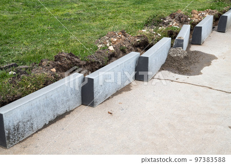 New curbs stand at the edge of the sidewalk. Preparing to repair road 97383588