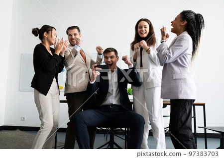 jubilant business team looking at the smartphone screen jubilant business team looking at the smartphone screen 97383703