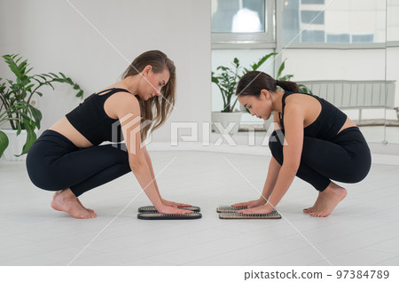 Caucasian and Asian women keep their hands on sadhu boards. Nailing practice. 97384789