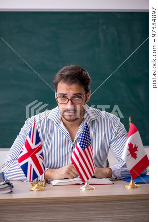 Young male English language teacher sitting in the classroom Young male English language teacher sitting in the classroom 97384897