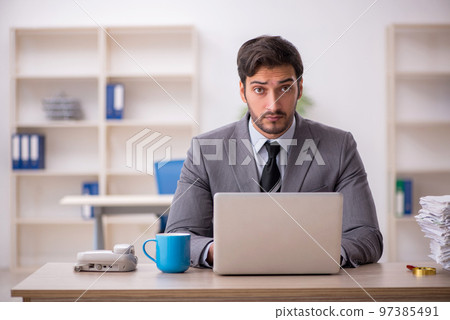 Young male employee and too much work in the office 97385491