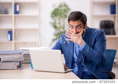 Young male employee and too much work in the office 97385503