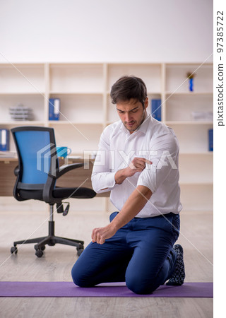 Young male employee doing sport exercises during break 97385722