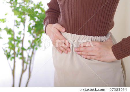 young woman with hands on lower abdomen 97385954